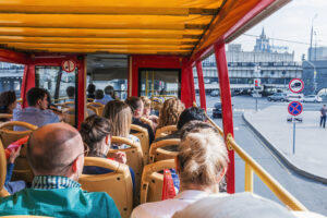 Passengers sit on the open top deck of a sightseeing bus
